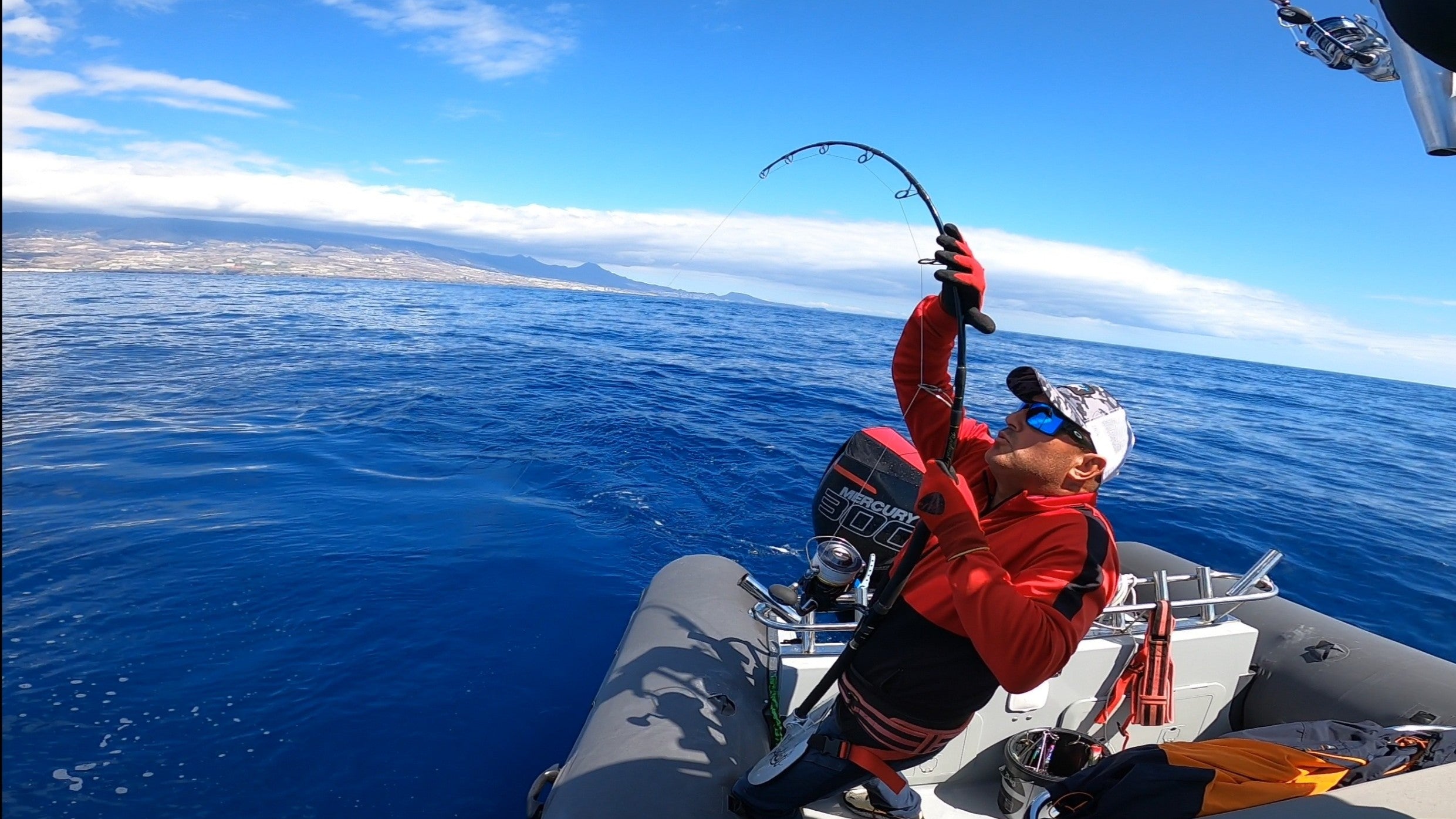 Pescador en un barco trabajando un gran pez que ha capturado