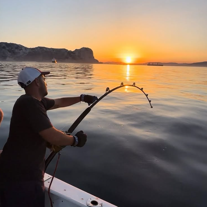 Pescador capturando un gran atún al curricán con un equipo pesado 